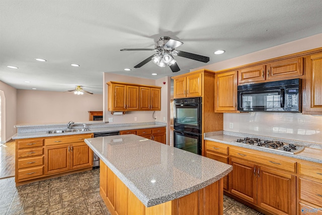 kitchen featuring ceiling fan, sink, tasteful backsplash, a kitchen island, and black appliances