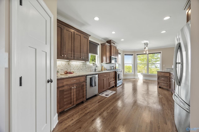 kitchen with crown molding, a healthy amount of sunlight, dark wood finished floors, and stainless steel appliances