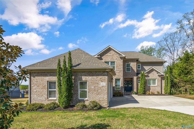 view of front of property with a front yard, roof with shingles, brick siding, and concrete driveway