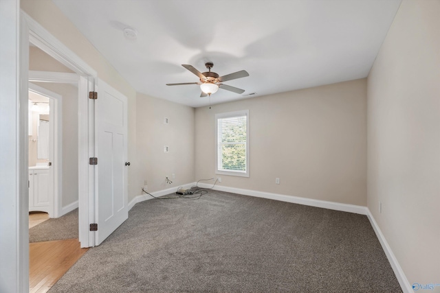 carpeted spare room with visible vents, baseboards, and ceiling fan