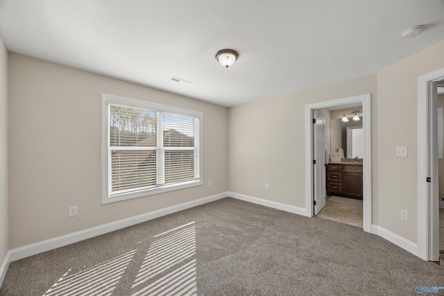 unfurnished bedroom with visible vents, baseboards, connected bathroom, and carpet