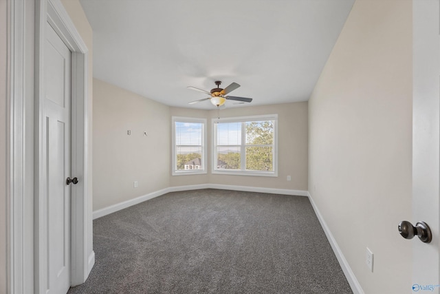 spare room with dark carpet, baseboards, and a ceiling fan