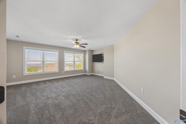 spare room featuring dark carpet, ceiling fan, baseboards, and visible vents