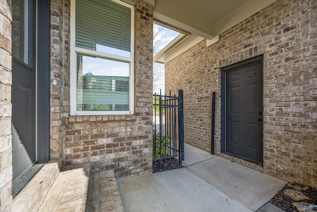 doorway to property featuring brick siding and a gate
