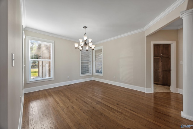 unfurnished dining area featuring baseboards, an inviting chandelier, crown molding, and wood finished floors