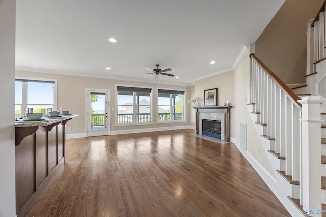 unfurnished living room with wood finished floors, ceiling fan, a fireplace, and stairway