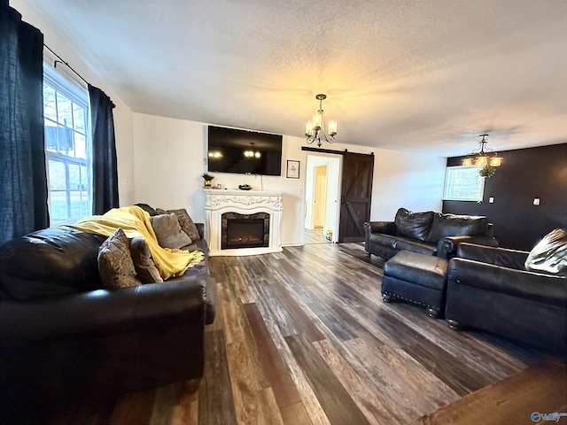 living room featuring hardwood / wood-style flooring, a barn door, a healthy amount of sunlight, and a notable chandelier