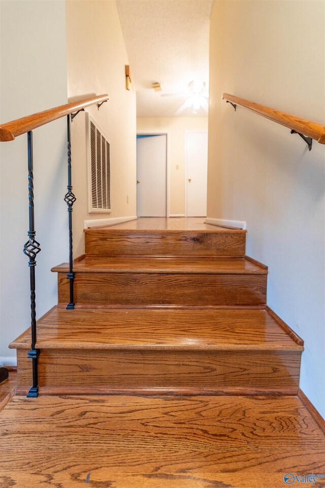 staircase featuring baseboards and visible vents