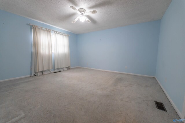 carpeted empty room with visible vents, a ceiling fan, a textured ceiling, and baseboards