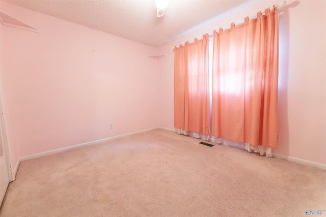 empty room featuring visible vents, a textured ceiling, carpet, and baseboards