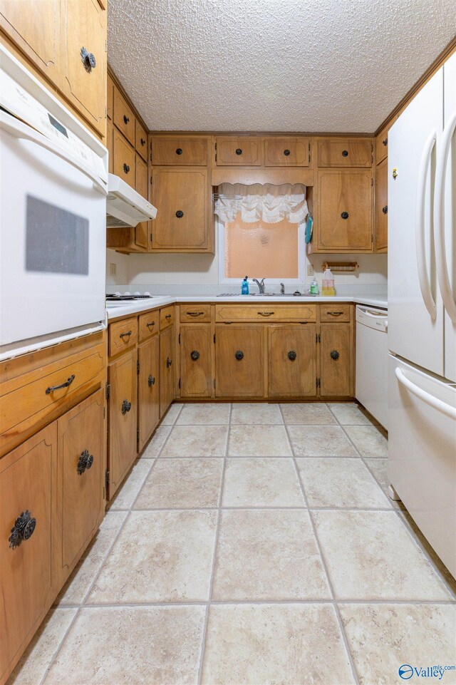 kitchen featuring white appliances, a textured ceiling, under cabinet range hood, and light countertops