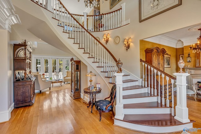 staircase featuring crown molding, hardwood / wood-style floors, a high ceiling, and french doors