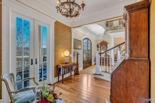 entryway with an inviting chandelier, light hardwood / wood-style flooring, french doors, and ornamental molding