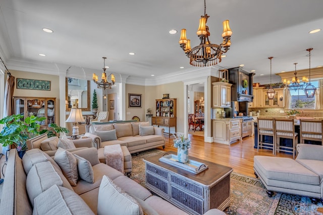 living room with ornamental molding, light wood-type flooring, and a notable chandelier