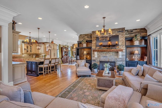 living room featuring light wood-type flooring, ornamental molding, and a fireplace