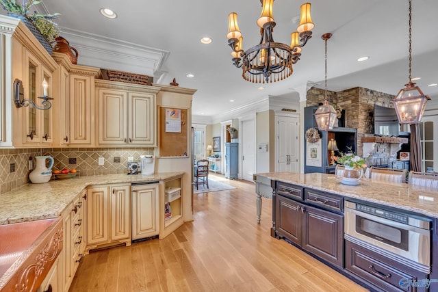 kitchen featuring light stone counters, hanging light fixtures, crown molding, backsplash, and light wood-type flooring