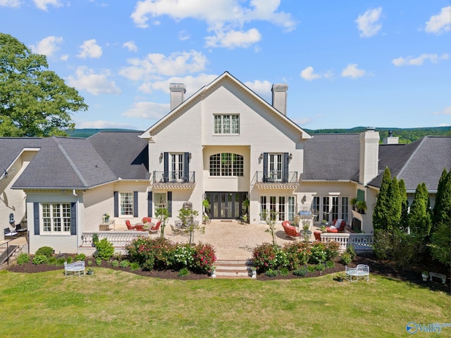 rear view of property with a patio area, a yard, and a balcony