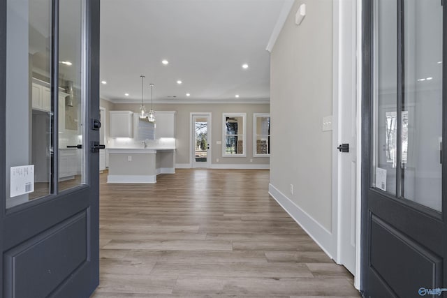 foyer with ornamental molding and light hardwood / wood-style flooring