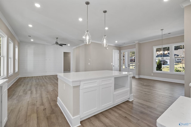 kitchen featuring white cabinets, hanging light fixtures, ceiling fan with notable chandelier, and a kitchen island