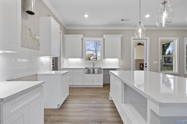 kitchen featuring sink, white cabinets, decorative light fixtures, and a kitchen island