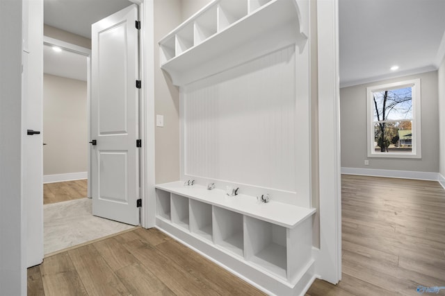 mudroom with light hardwood / wood-style floors and crown molding