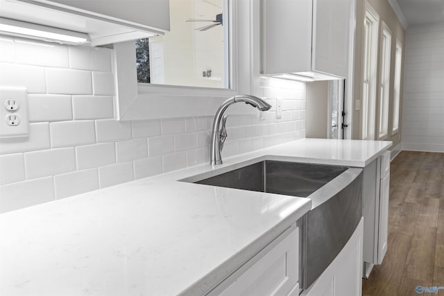 kitchen featuring light stone countertops, sink, dark wood-type flooring, decorative backsplash, and white cabinets