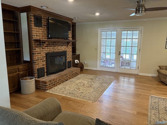 living room with wood finished floors, baseboards, ornamental molding, and a brick fireplace