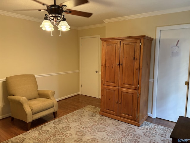 living area with crown molding, dark wood-style floors, a ceiling fan, and baseboards