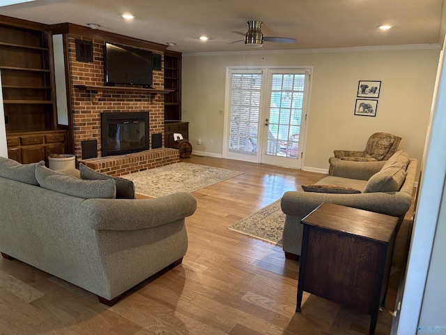 living area featuring baseboards, ornamental molding, a fireplace, wood finished floors, and a ceiling fan