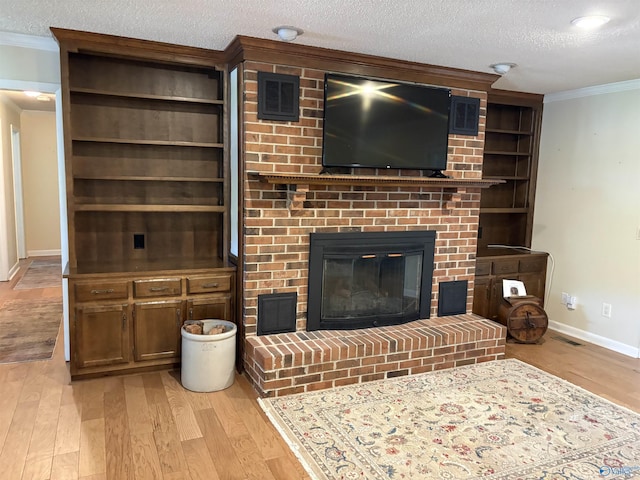 living room with light wood-style floors, a brick fireplace, crown molding, baseboards, and a textured ceiling