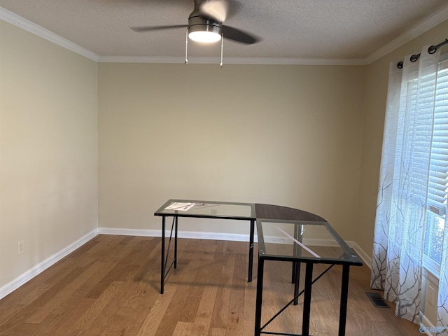 unfurnished office featuring ornamental molding, ceiling fan, a textured ceiling, and wood finished floors