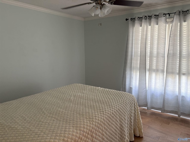 bedroom featuring wood finished floors, crown molding, and a ceiling fan