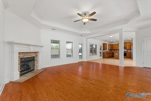 unfurnished living room featuring ornamental molding, light wood-type flooring, and a raised ceiling