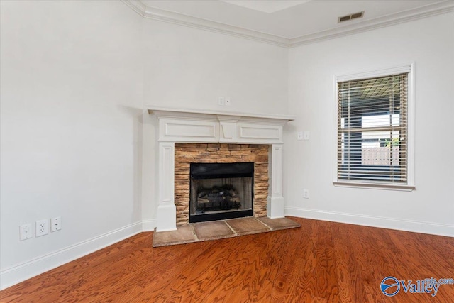 unfurnished living room featuring crown molding, a stone fireplace, and wood-type flooring