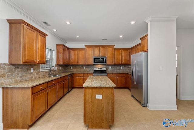 kitchen with light stone counters, backsplash, appliances with stainless steel finishes, sink, and a center island