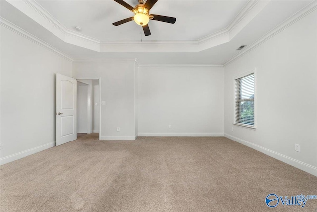 unfurnished room featuring ornamental molding, light carpet, a tray ceiling, and ceiling fan