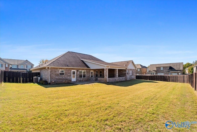 rear view of property with central air condition unit and a lawn