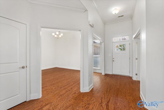 foyer entrance with ornamental molding, a chandelier, and hardwood / wood-style floors