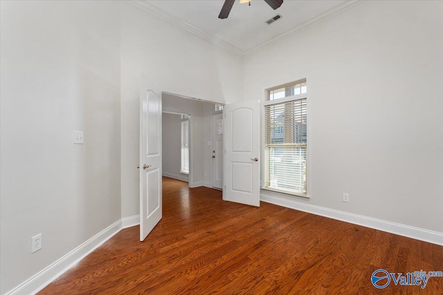 unfurnished room featuring ceiling fan, ornamental molding, a high ceiling, and hardwood / wood-style floors