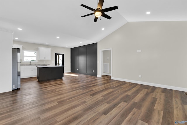 unfurnished living room with a ceiling fan, lofted ceiling, dark wood-style flooring, and visible vents