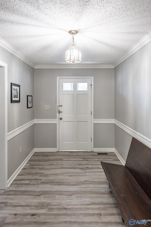 foyer entrance with crown molding, a chandelier, a textured ceiling, and light wood-type flooring