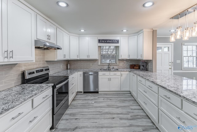 kitchen with sink, white cabinetry, appliances with stainless steel finishes, pendant lighting, and decorative backsplash