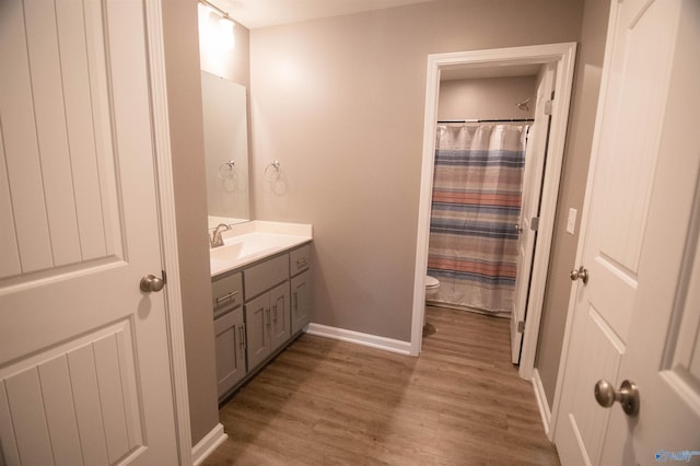 bathroom featuring hardwood / wood-style flooring, toilet, vanity, and a shower with curtain