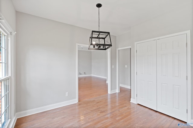 unfurnished dining area with a chandelier and light hardwood / wood-style floors