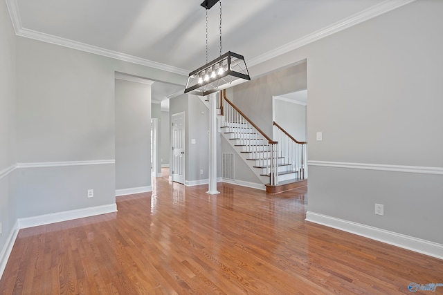 unfurnished dining area featuring an inviting chandelier, ornamental molding, and hardwood / wood-style flooring