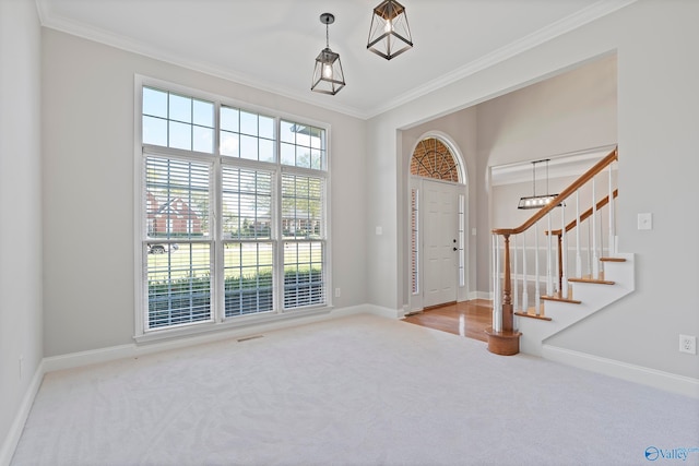 carpeted entrance foyer featuring a notable chandelier and ornamental molding