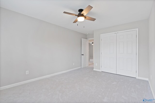 unfurnished bedroom with ceiling fan, a closet, and light colored carpet