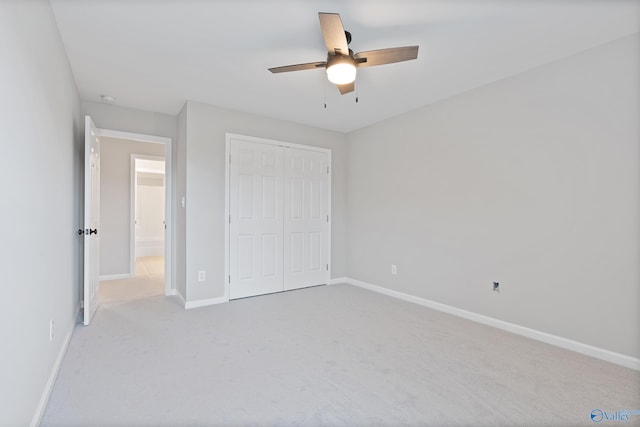 unfurnished bedroom with light colored carpet, a closet, and ceiling fan