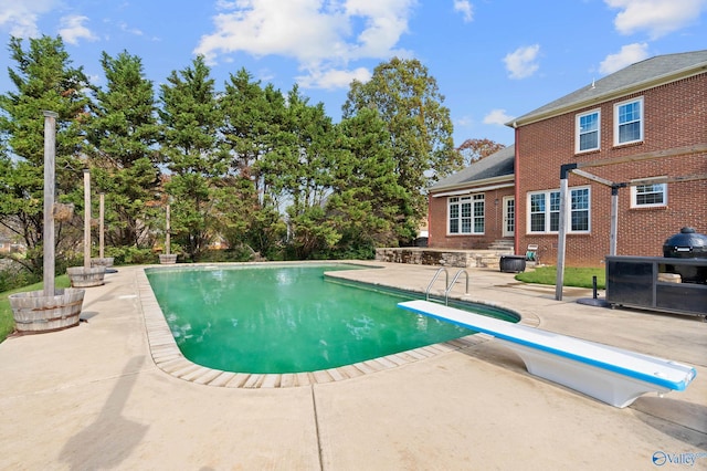 view of swimming pool featuring a patio and a diving board