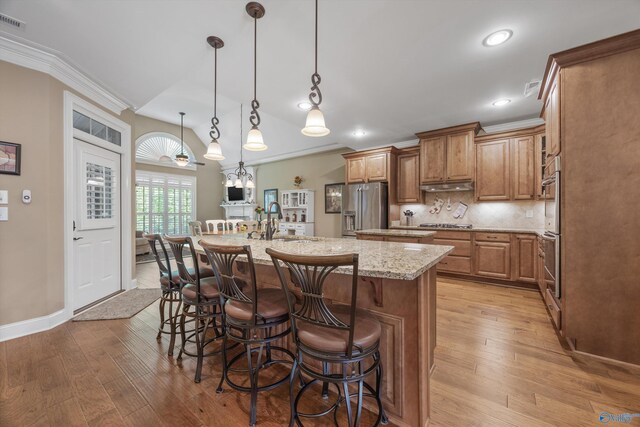 39 Verdant Cir, Huntsville, AL 35803 - kitchen featuring appliances with stainless steel finishes, brown cabinetry, light wood-type flooring, light stone counters, and crown molding